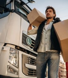 Shipping conception, with boxes. Truck driver is near the transport outdoors